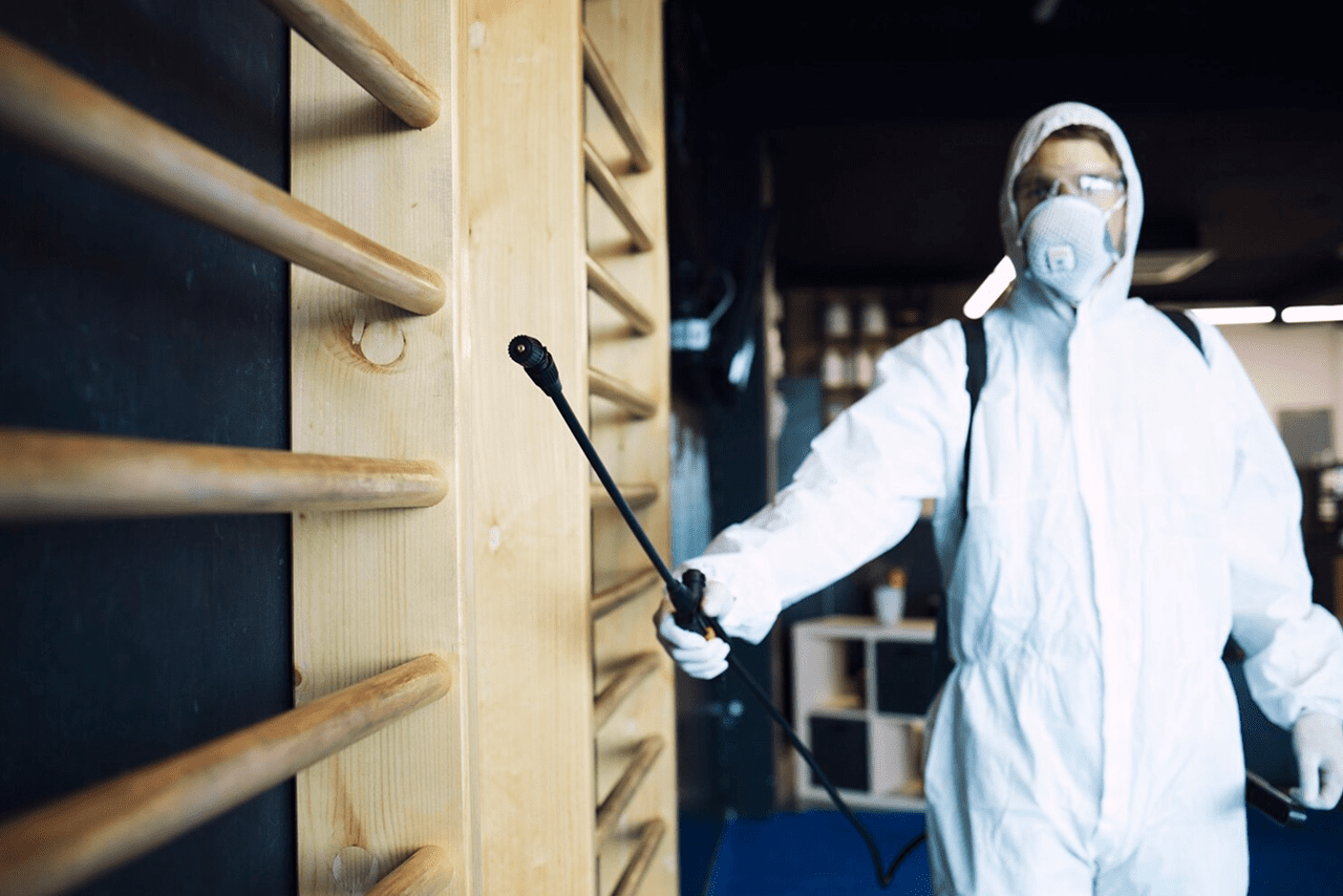 Pest control technician spraying treatment inside a building