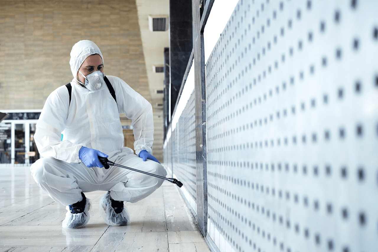 Pest control technician treating an exterior building surface