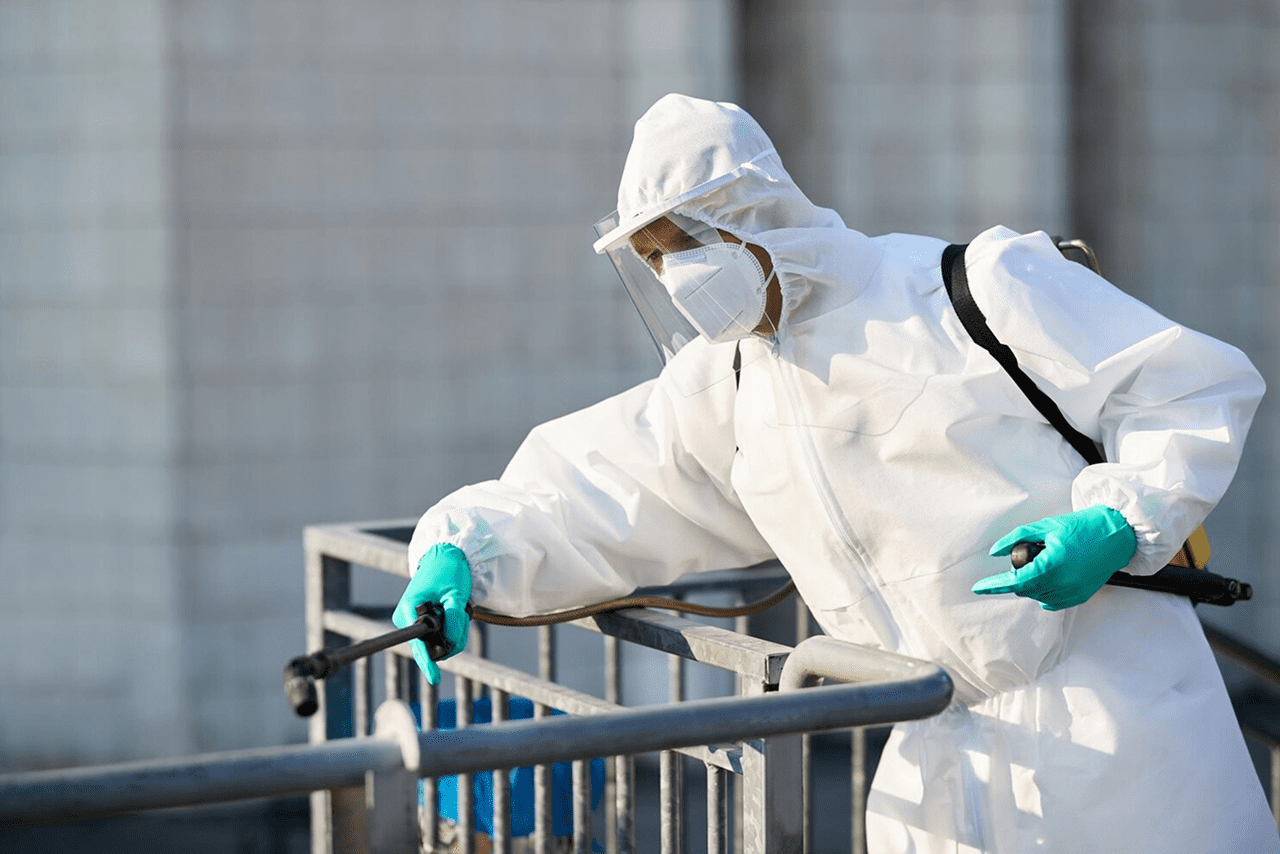Pest control technician spraying treatment on an outdoor railing