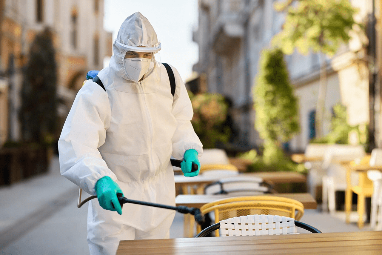 Pest control technician spraying treatment around an outdoor dining area